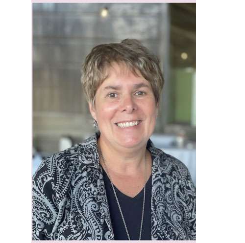 Kim Fenn Kim Fenn, Medical Assistant and Operations Manager for Full Circle America (FCA) wearing and black and white jacket over a black shirt with short blond hair