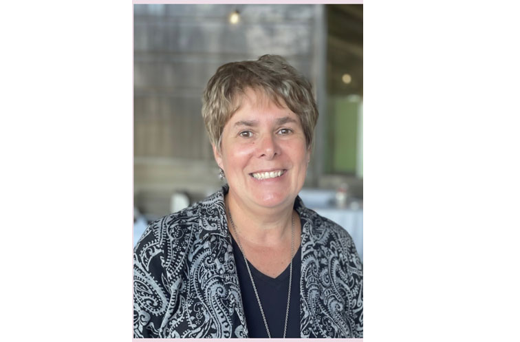 Kim Fenn Kim Fenn, Medical Assistant and Operations Manager for Full Circle America (FCA) wearing and black and white jacket over a black shirt with short blond hair